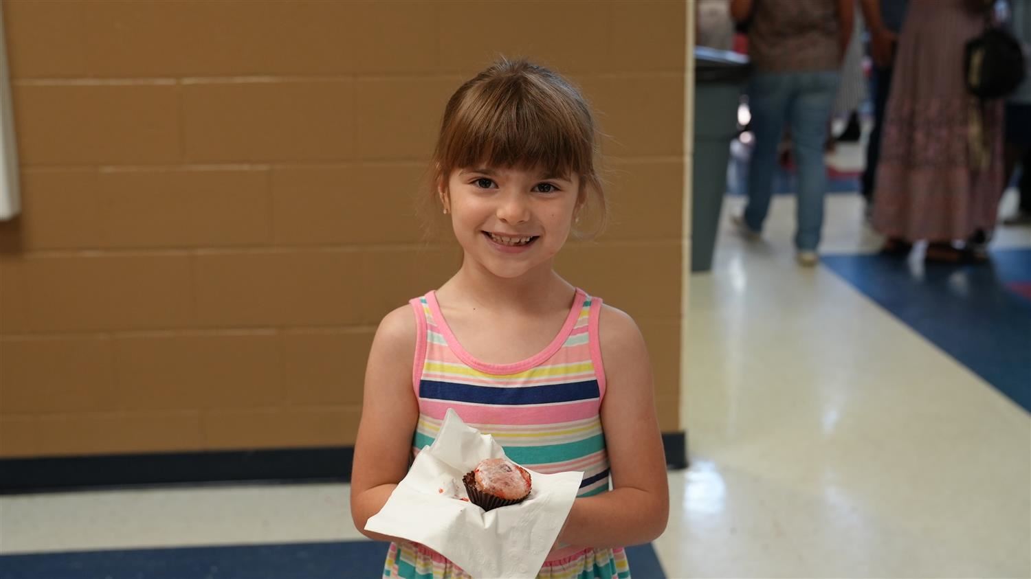 Girl enjoying a strawberry cupcake.